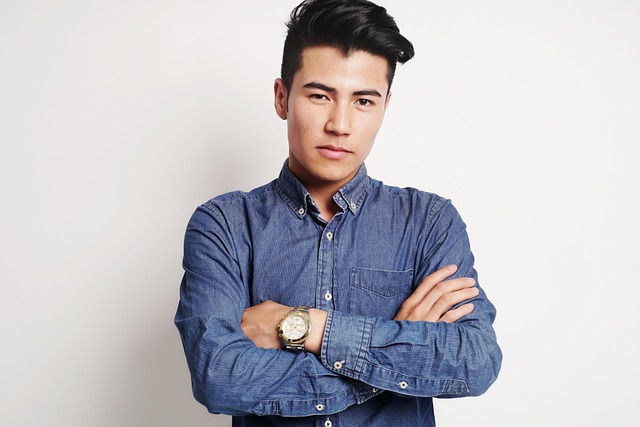 Professional headshot portrait of a young Black British man in his early thirties wearing a forest green shirt, photographed in a modern warehouse environment with stacked boxes of artisan food products