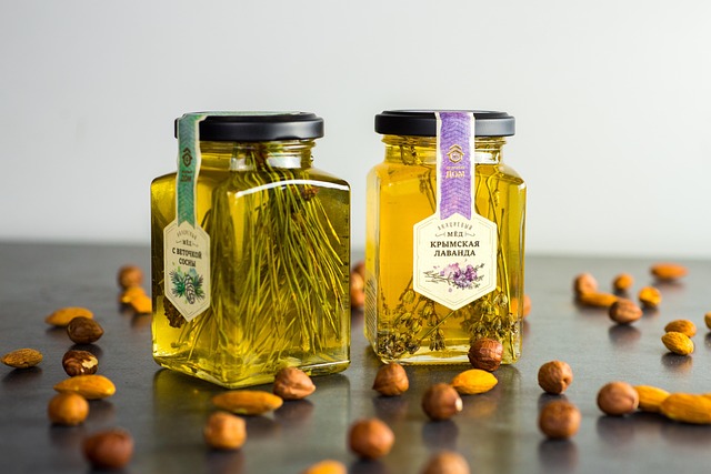 Premium Manuka honey in an elegant hexagonal glass jar with gold lid photographed with a wooden honey dipper dripping thick golden honey on a marble countertop