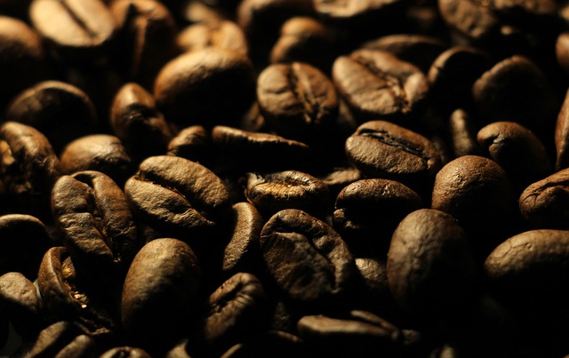 Kraft paper bag of single-origin Ethiopian Yirgacheffe coffee beans with some beans scattered on a white marble surface alongside a ceramic pour-over coffee dripper